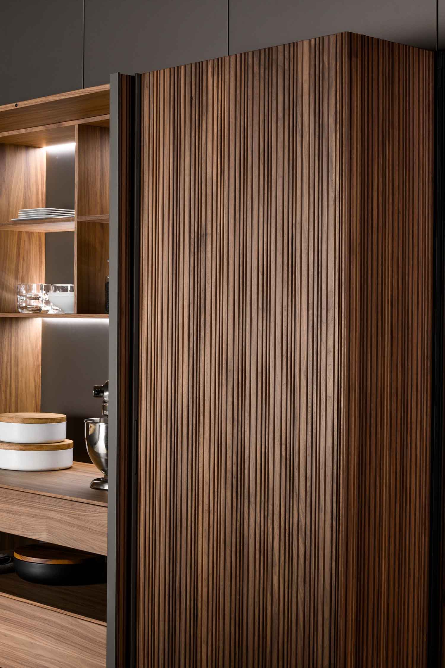 Luxurious vertically milled walnut veneer covers the kitchen wall units.