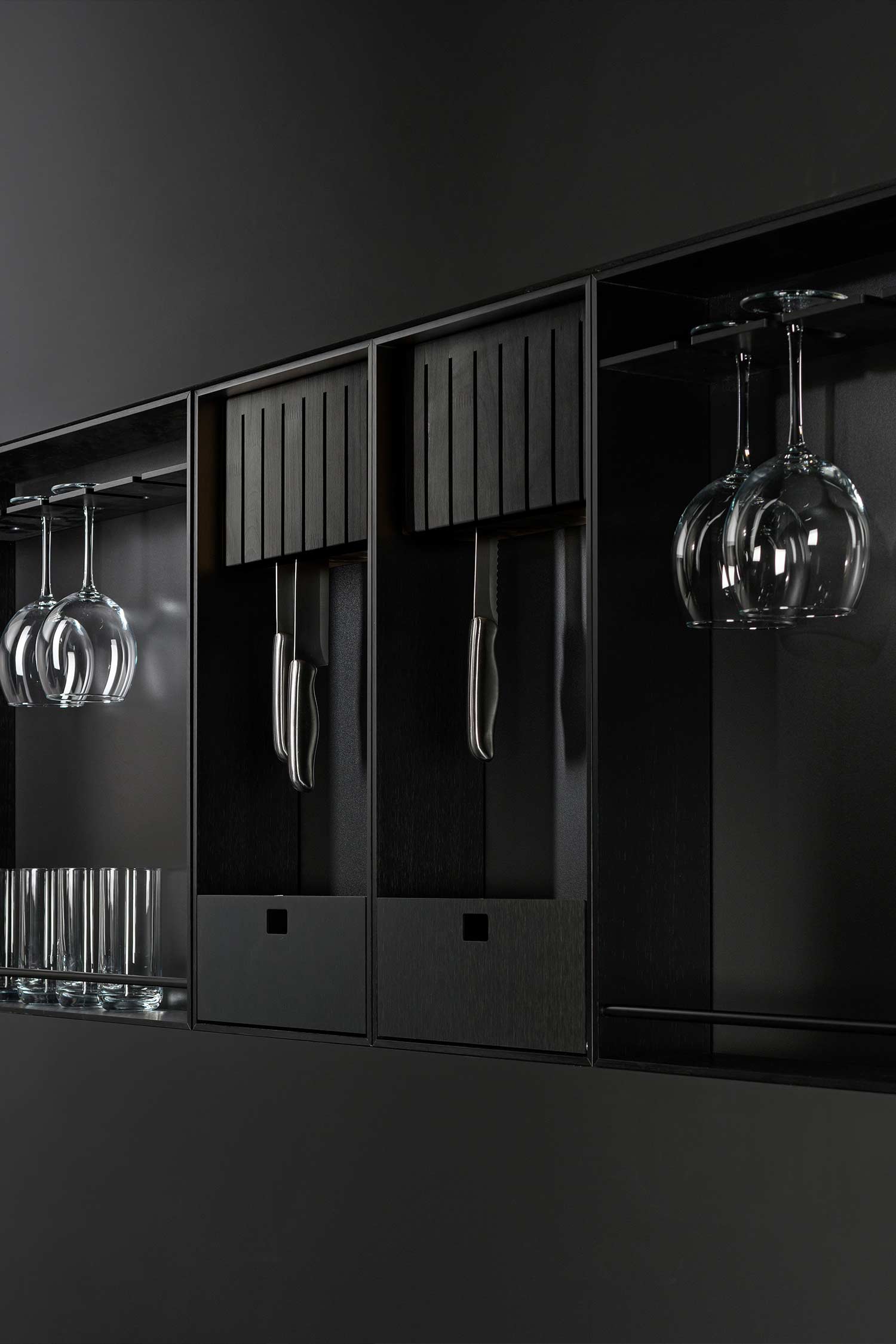 Modular elements build a exposed metal wall mounted storage unit for glassware, cooking knives and serveware.