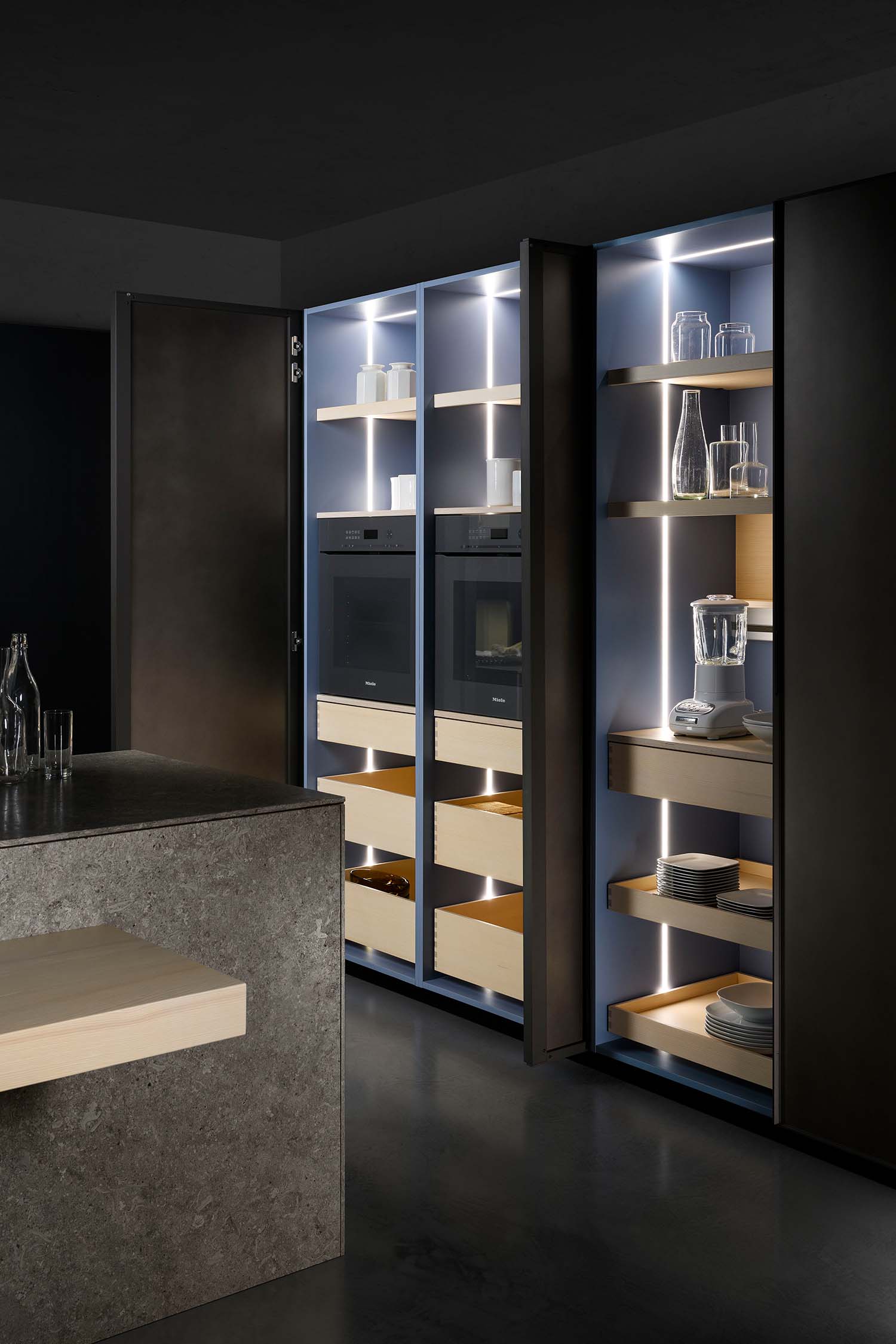 Large tall units contain and hide large integrated kitchen appliances and hidden storage, all finished in luxury Scandinavian style wood veneer.