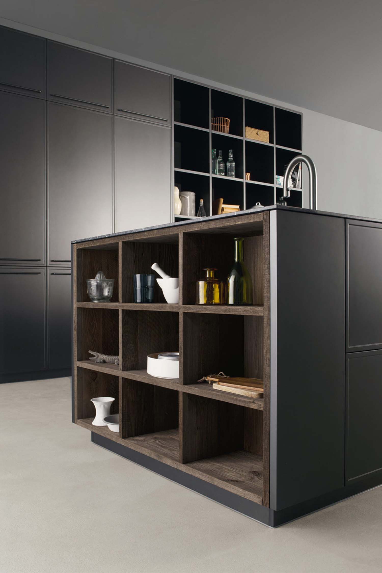 Open storage elements allow for inventory or decoration at the edge of the kitchen island.