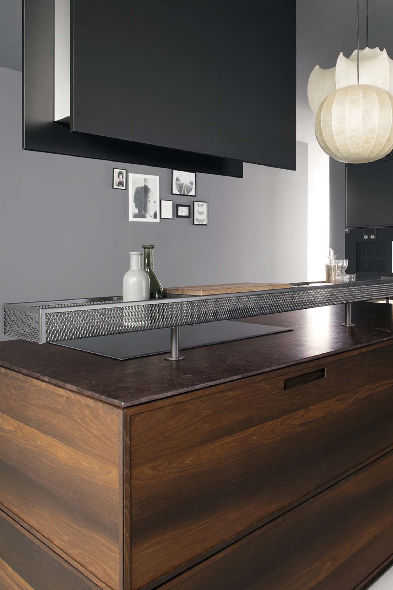 A close-up of a kitchen drawer opened to reveal an organized cutlery and utensil insert. The insert is made of a dark wood with black dividers, showcasing a sleek and efficient storage solution.