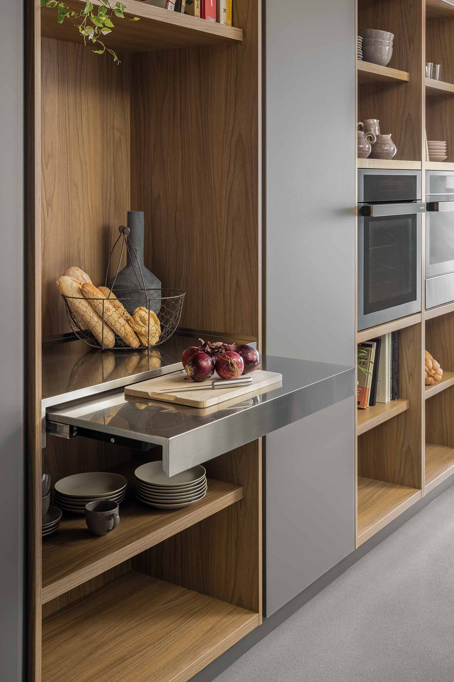 A close-up view of the kitchen island's wooden snack bar and an integrated black induction hob. The contrasting materials highlight the elegant and functional design.