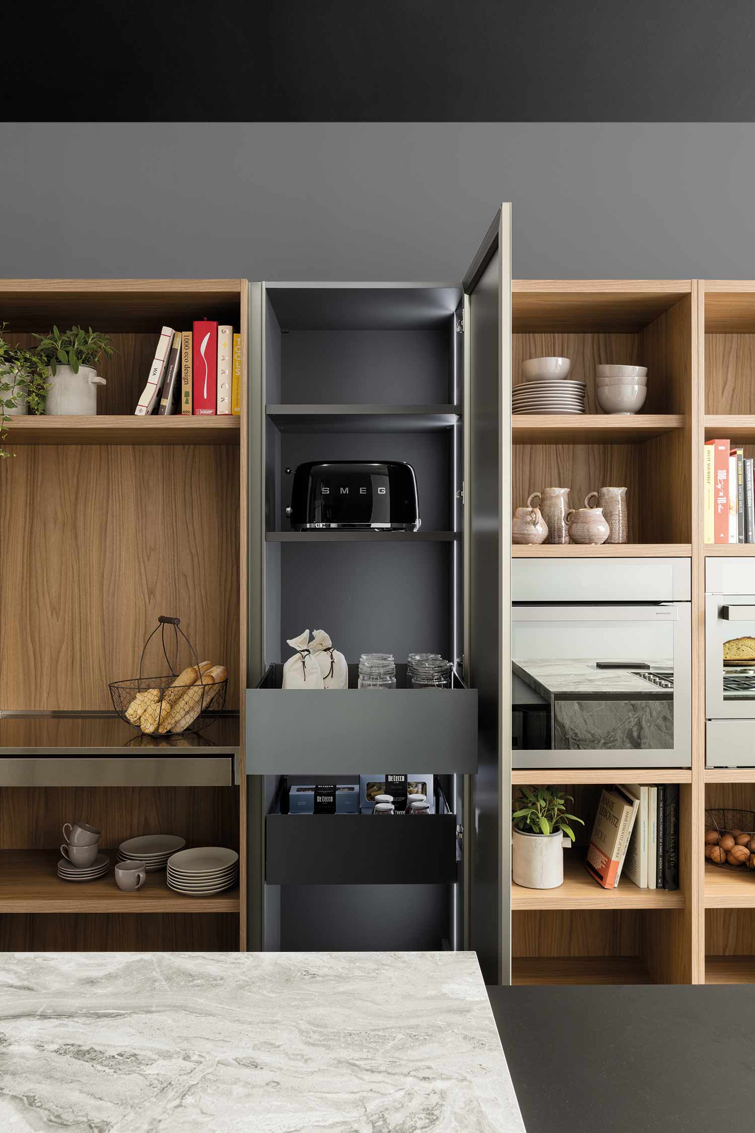 A detail shot of a kitchen's built-in, vertical pantry or tall unit. The open doors reveal several shelves and an internal lighting system.