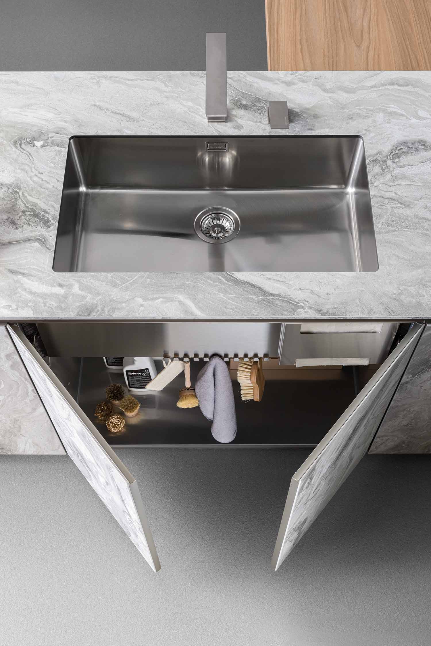 A close-up of a kitchen's marble-effect countertop and an integrated sink with a sleek, minimalist faucet. The seamless design emphasizes the clean lines of the space.