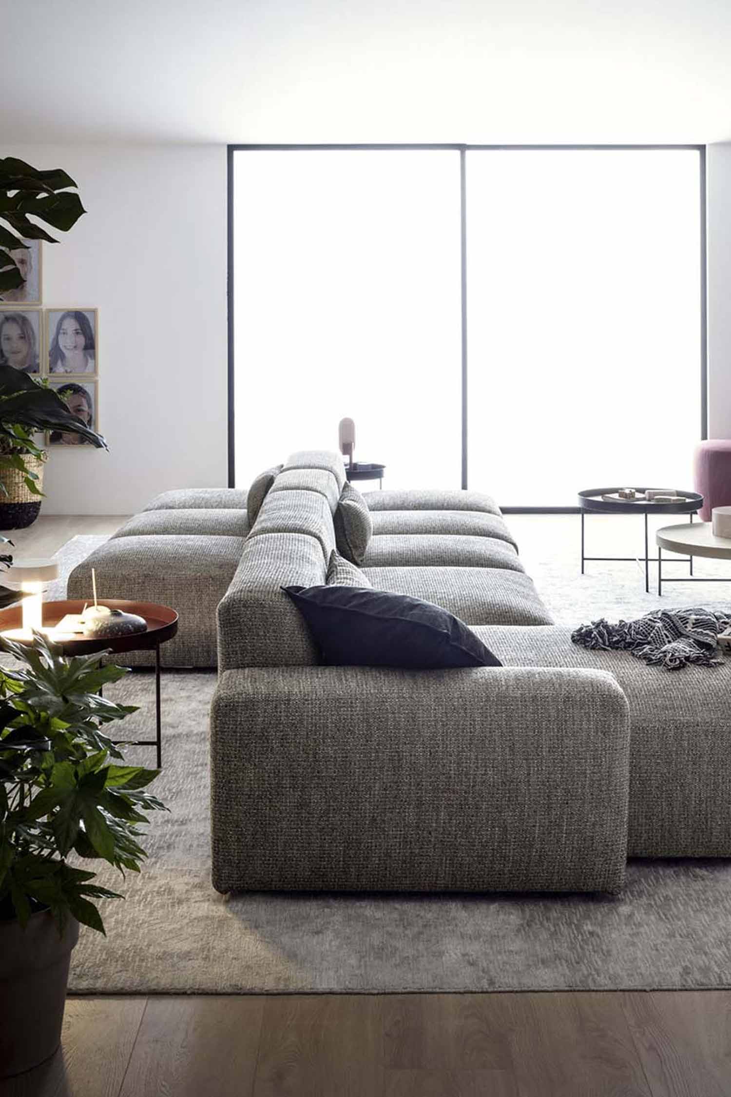 An overhead view of a gray modular sofa with a textured fabric. There are two black pillows and a black and white patterned throw blanket on the sofa, along with some books and wooden blocks.