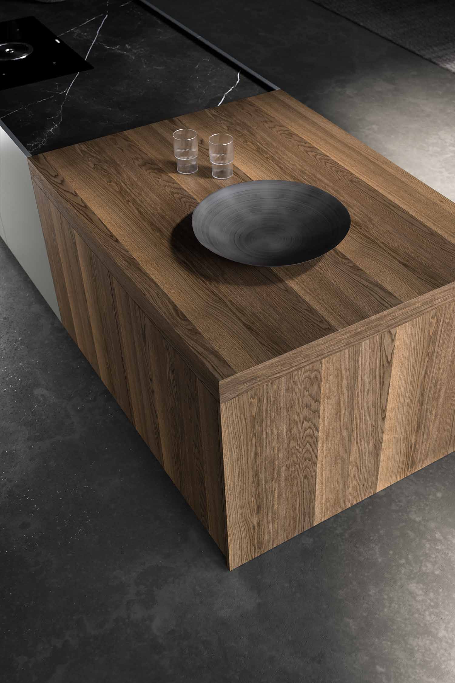 A detail of a minimalist kitchen wall with a black metal frame holding a single, decorative bowl. The wall itself is a textured, light-grey finish, possibly concrete.