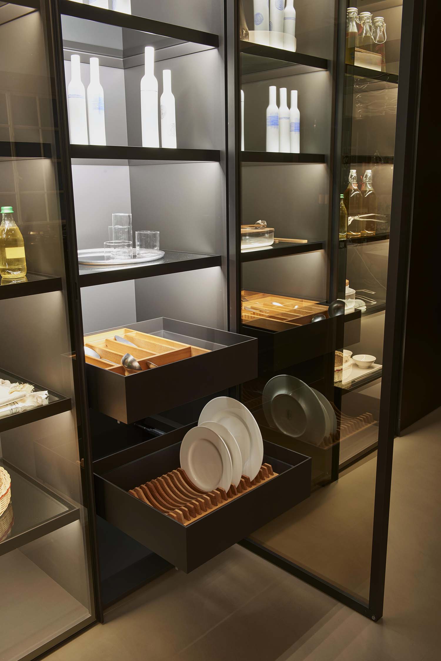 A close-up, high-angle shot of a minimalist, integrated kitchen hob. The black induction surface is flush-mounted into a light-colored, white marble countertop.