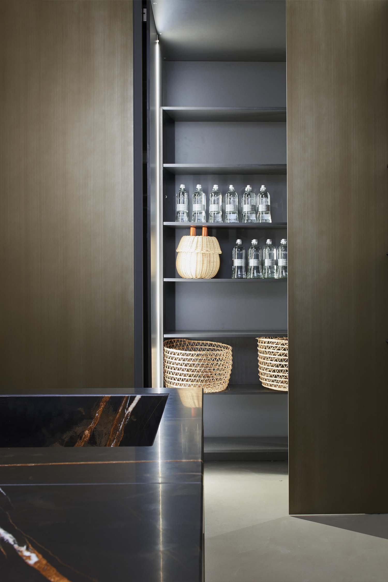 A detail shot of a kitchen's built-in pantry. The pantry has a light-colored, polished surface and contains a hidden, built-in coffee machine on a pull-out shelf.
