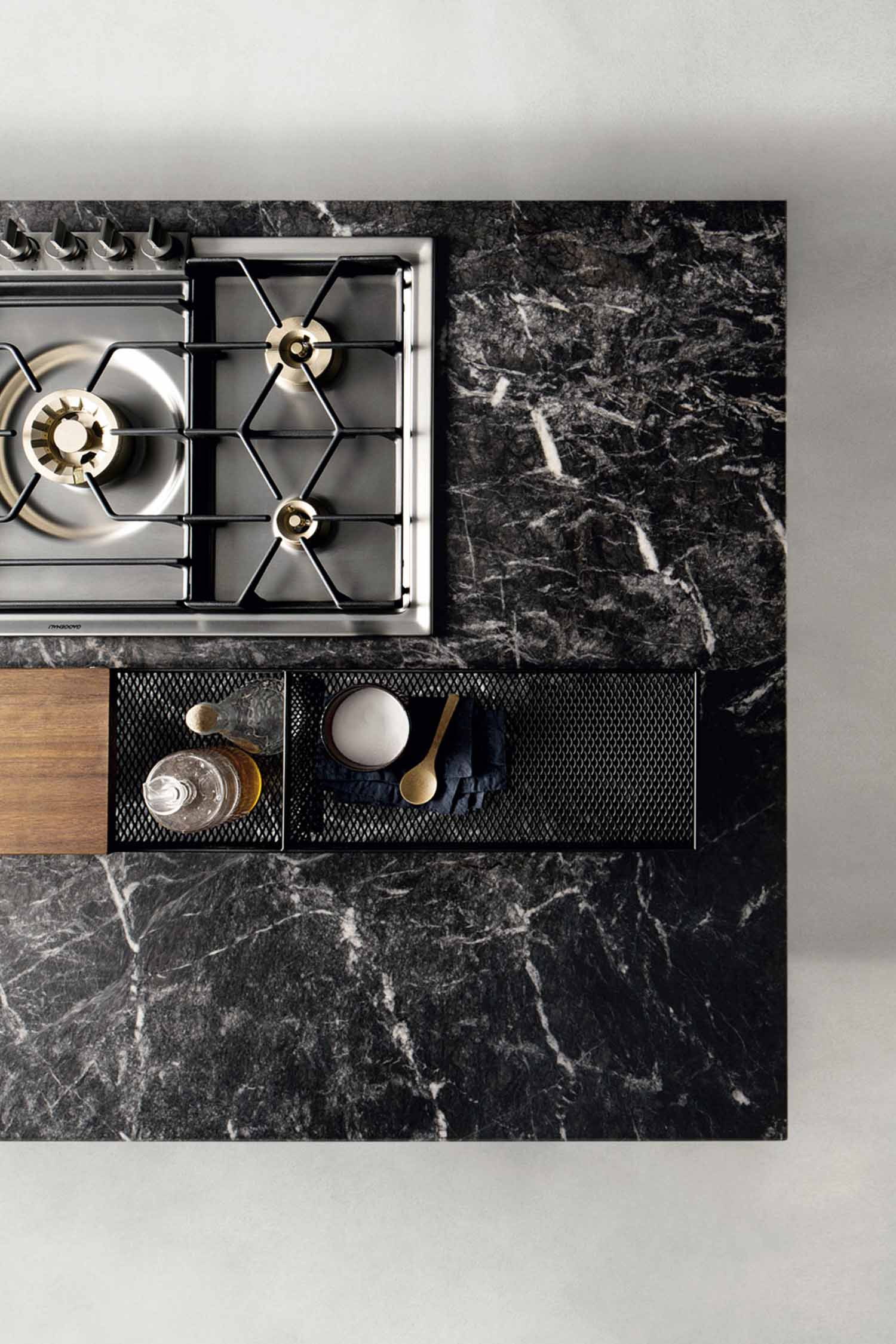 A close-up detail of a modern, minimalist sink area. The kitchen has a light-colored countertop and a sleek, rectangular, integrated sink with a black, minimalist faucet. Showcasing a black veined marble worktop.