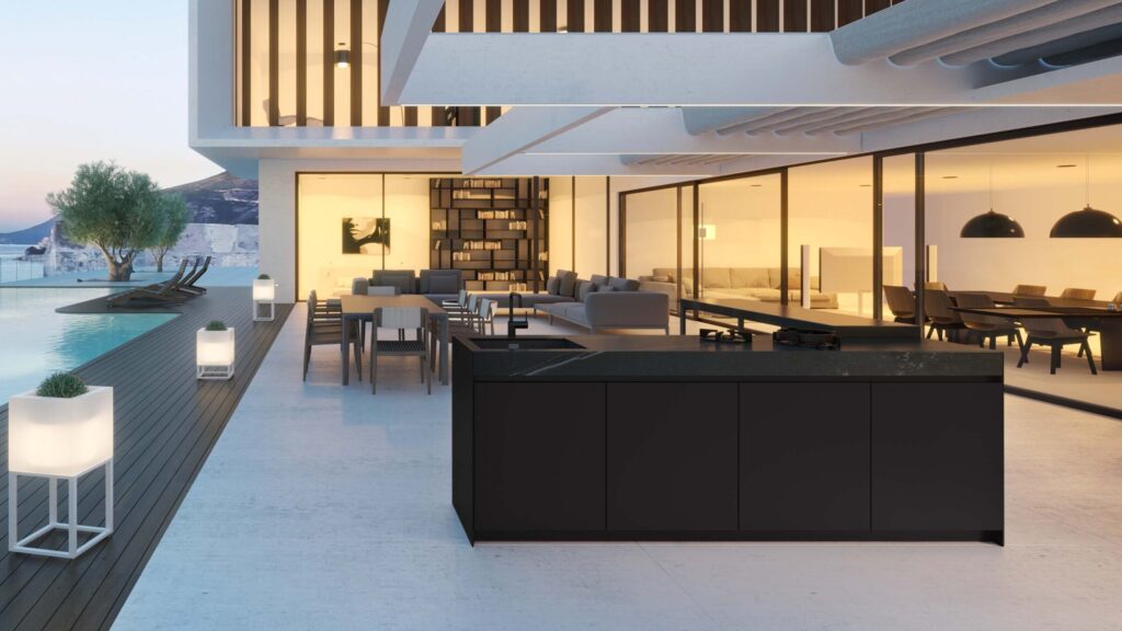 High-end modular outdoor kitchen in a dark finish set on a patio, featuring a large worktop, built-in grill, and dedicated storage cabinets.