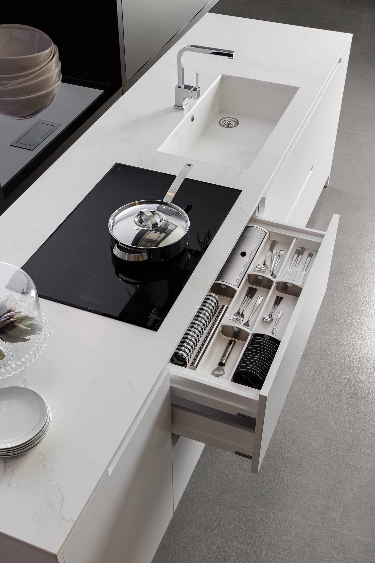 An image of an open tall cabinet, revealing a home bar or wine storage area. The cabinet, with a dark wood-grain exterior, contains built-in shelves for hanging wine glasses, a pull-out tray for a decanter and bottles, and a lower rack for storing wine bottles horizontally.