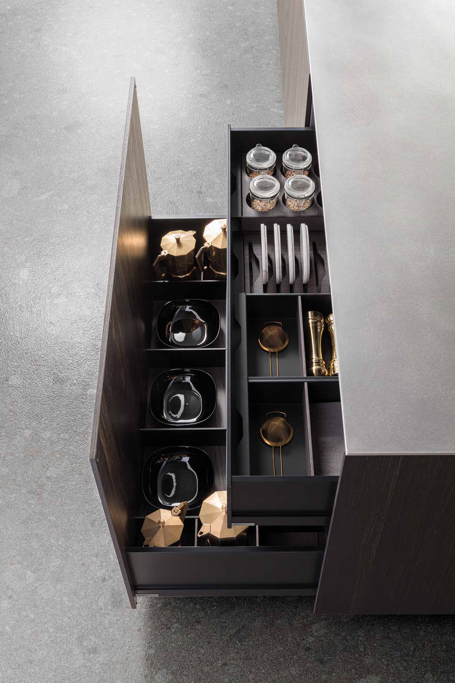 A detailed, low-angle shot of a kitchen island's stainless steel countertop where it meets the dark wood veneer base. The image highlights the clean, modern joinery and the contrasting textures.