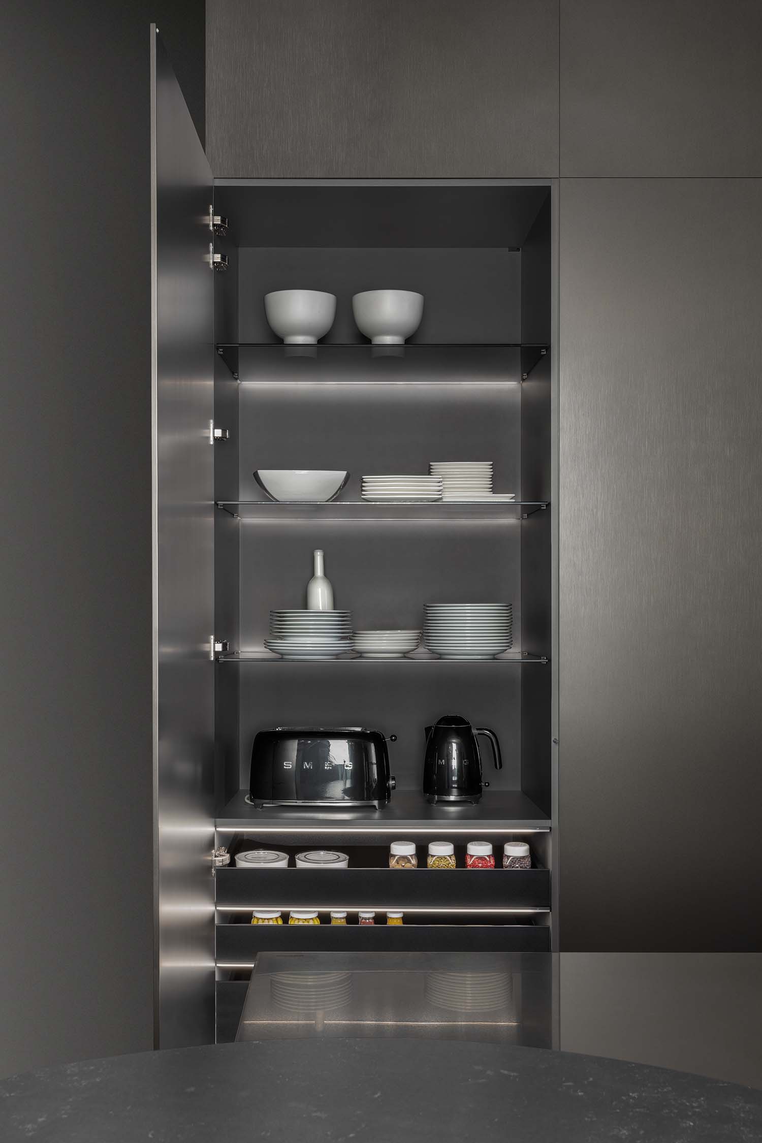 A close-up of a dark wood veneer cabinet with a horizontal, recessed groove that serves as a sleek, handleless pull. The wood has a visible grain texture.