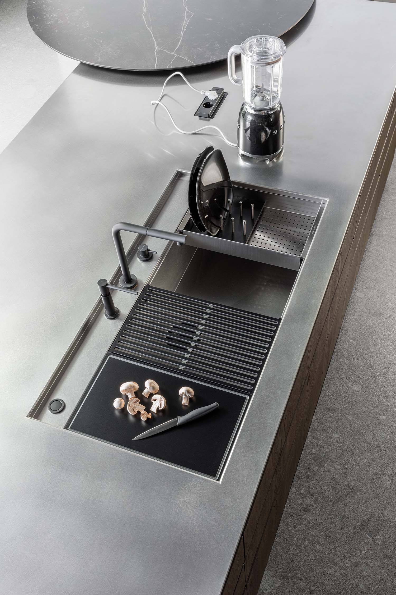 A detail of a wooden kitchen drawer with a pull-out wooden insert for organizing spices and small bottles. The insert is designed to keep everything neatly in place.