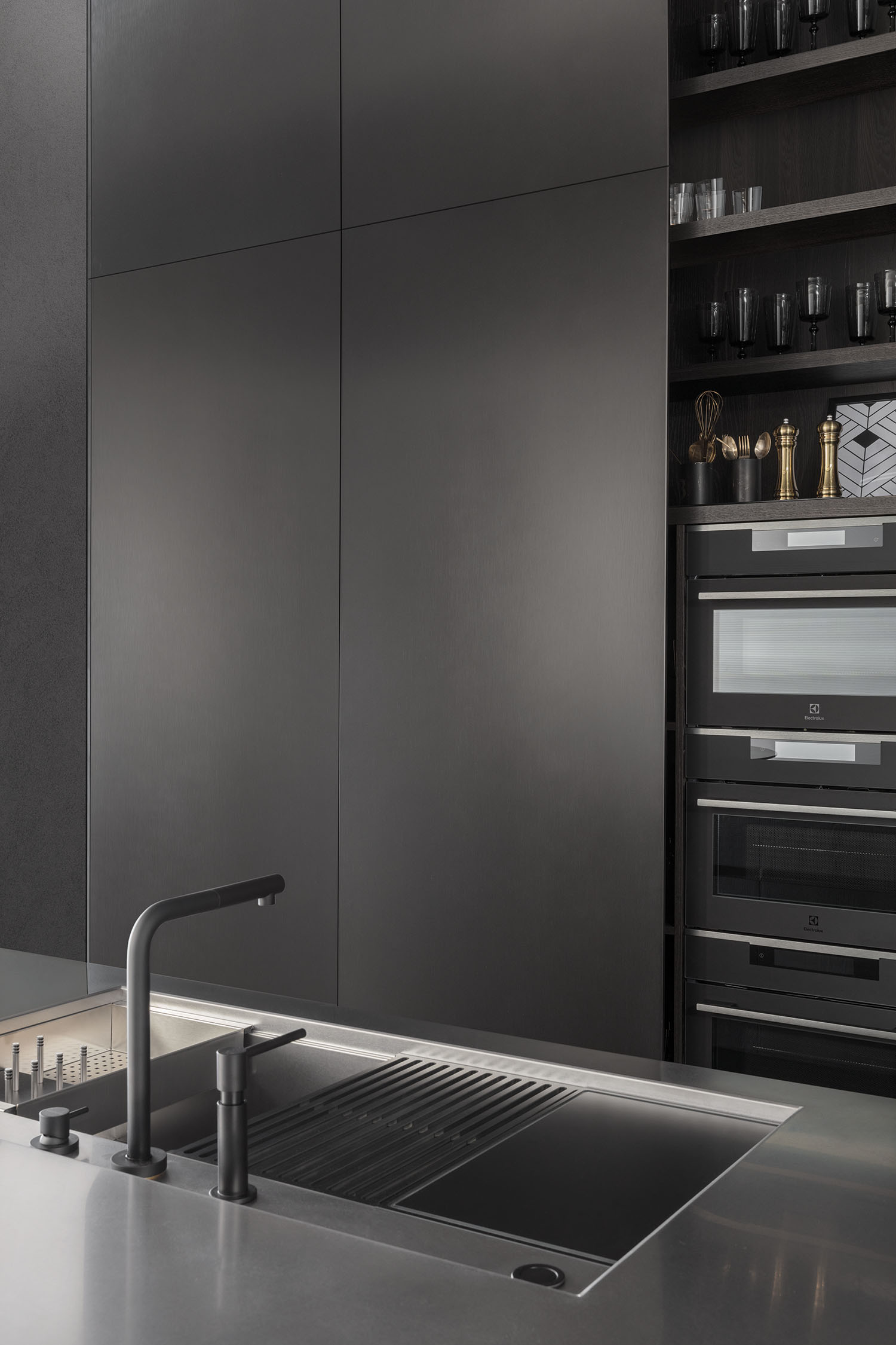 A side-angle shot of a dark wood veneer kitchen cabinet, showing its handleless design and the textured grain of the wood. The focus is on the simple, clean lines of the joinery.
