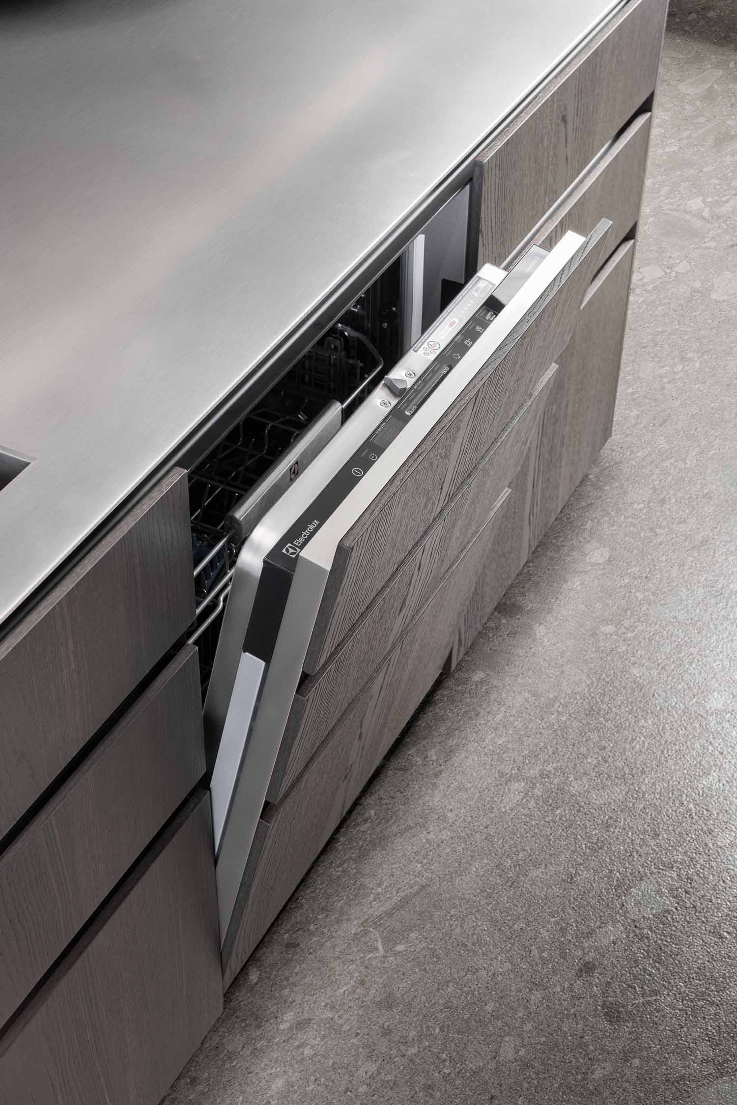 A close-up detail of a modern, built-in kitchen cabinet with a ridged, slatted texture on its doors, highlighting the craftsmanship and the play of light and shadow on the surface.