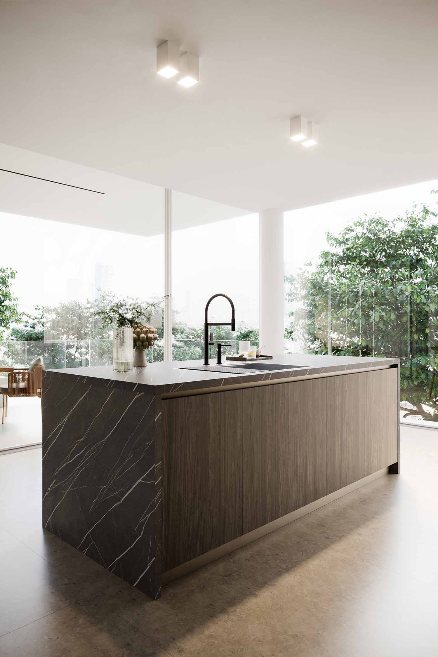 A close-up, low-angle shot of a minimalist kitchen island's sink area. The black countertop holds a sleek black faucet and an integrated sink with a black cover on one side, hinting at hidden functionality.