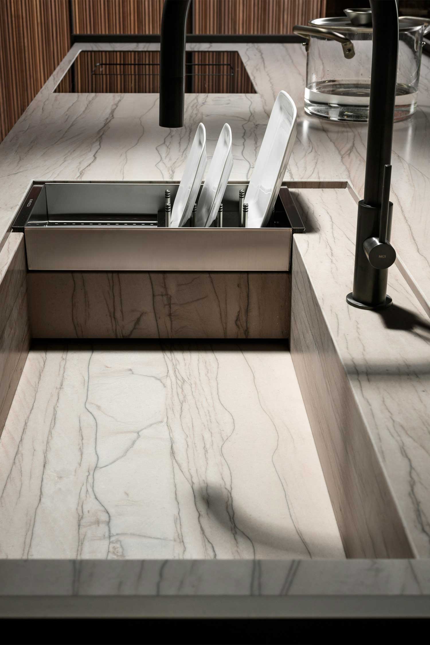 A close-up shot of a modern kitchen island's light-colored stone countertop, showcasing its surface texture and a seamless, integrated induction hob.