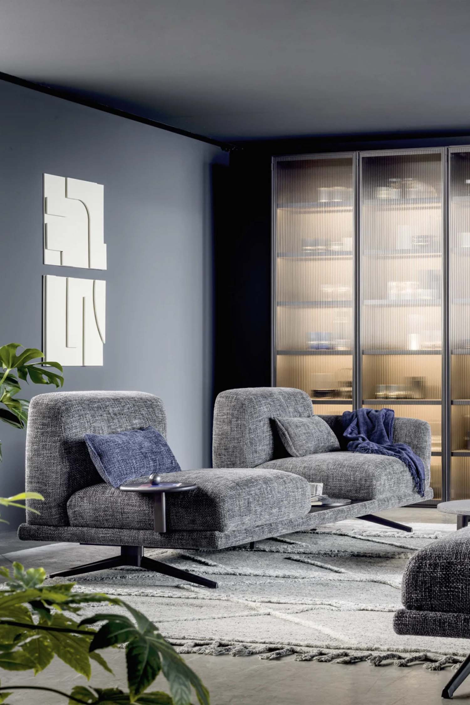 A close-up shot of the corner of a modern sofa. The photo focuses on the seamless stitching and rounded edge of the cushion, highlighting the quality of the craftsmanship. The light beige fabric and clean design are the main focus.