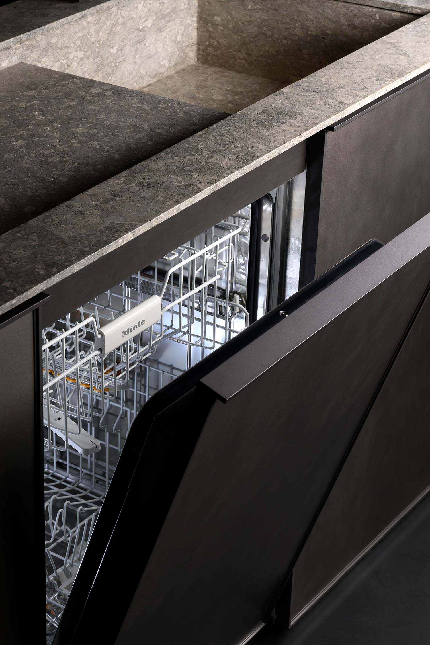 A close-up of a kitchen cabinet with a fluted or ridged surface. The cabinet door is a light, warm wood with a prominent vertical texture.