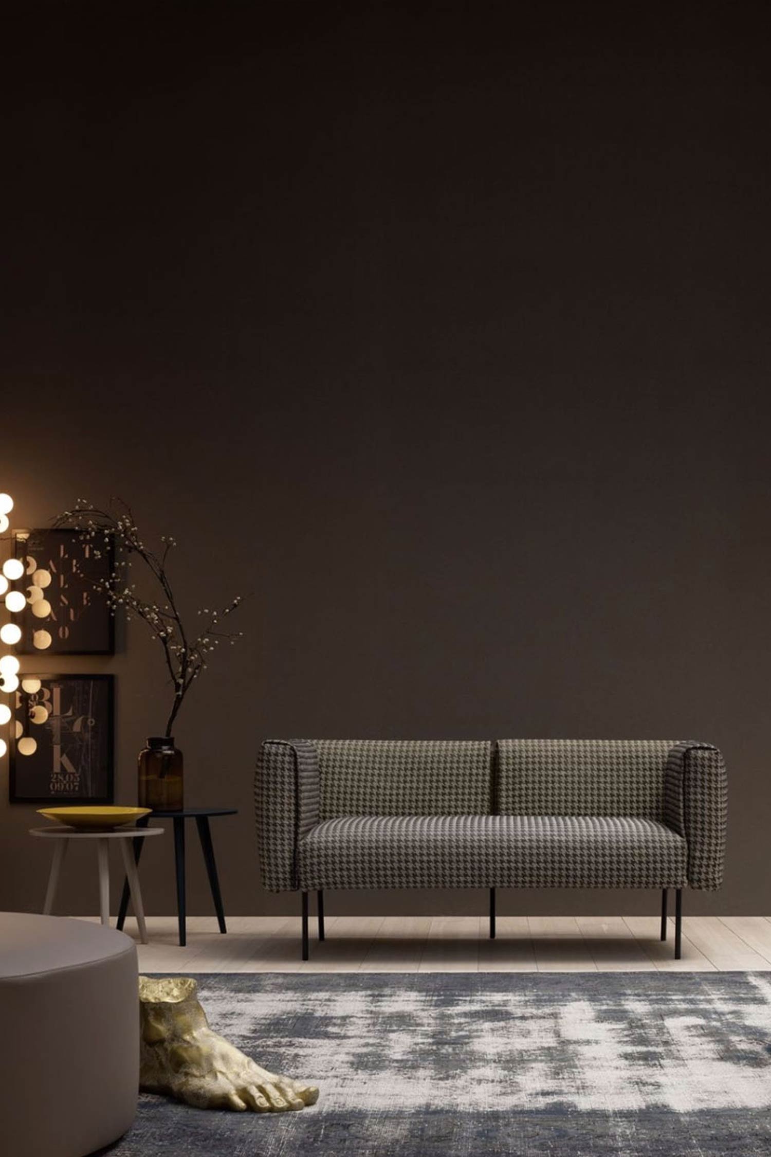 A modern living room with a two-seater sofa upholstered in a black and white houndstooth pattern, set against a dark brown wall. The room also features a small side table, a rug, and a light fixture.