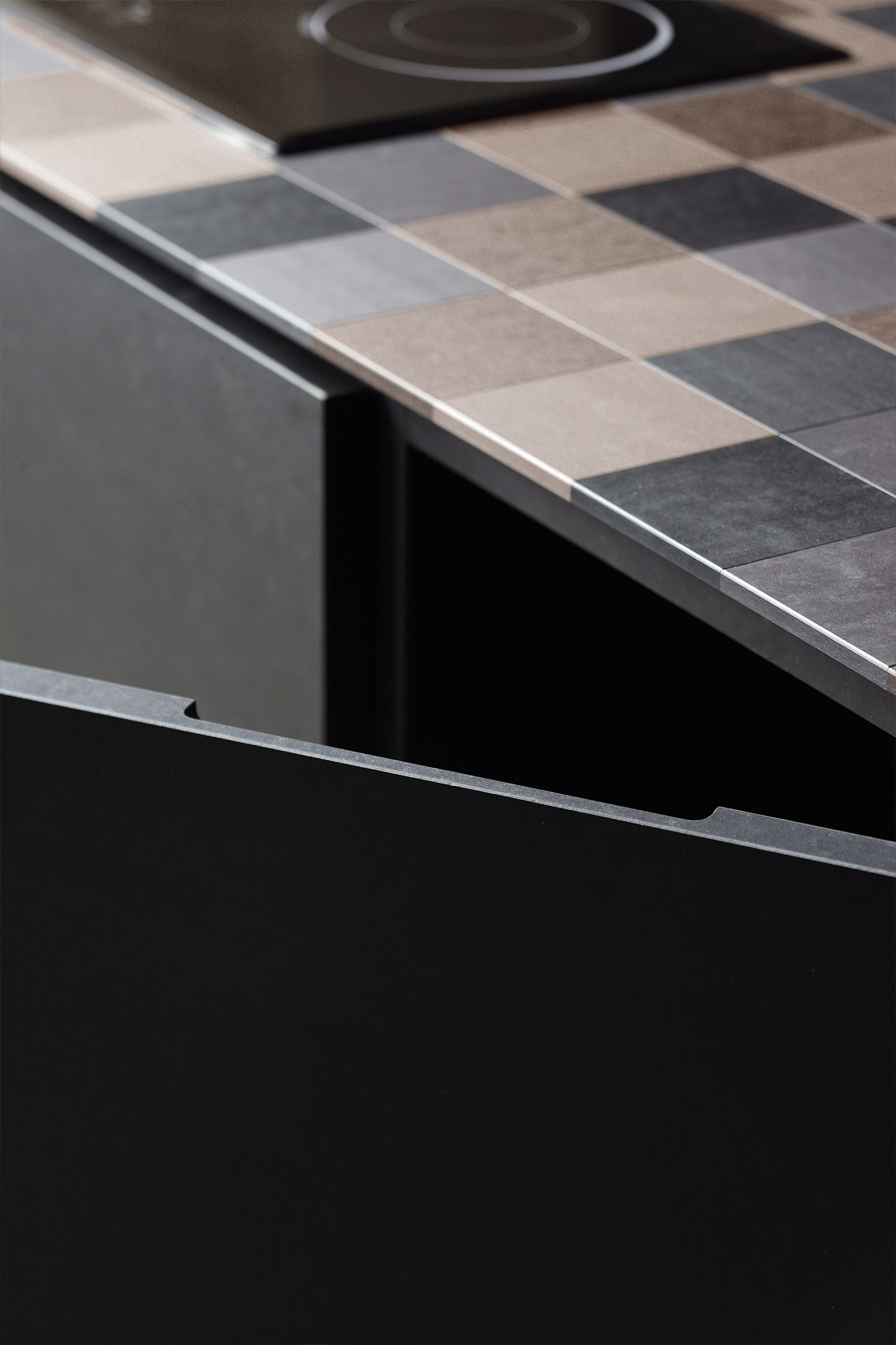 A detail shot of a modern, minimalist countertop and a sleek, rectangular sink. The countertop has a light, stone-like texture.