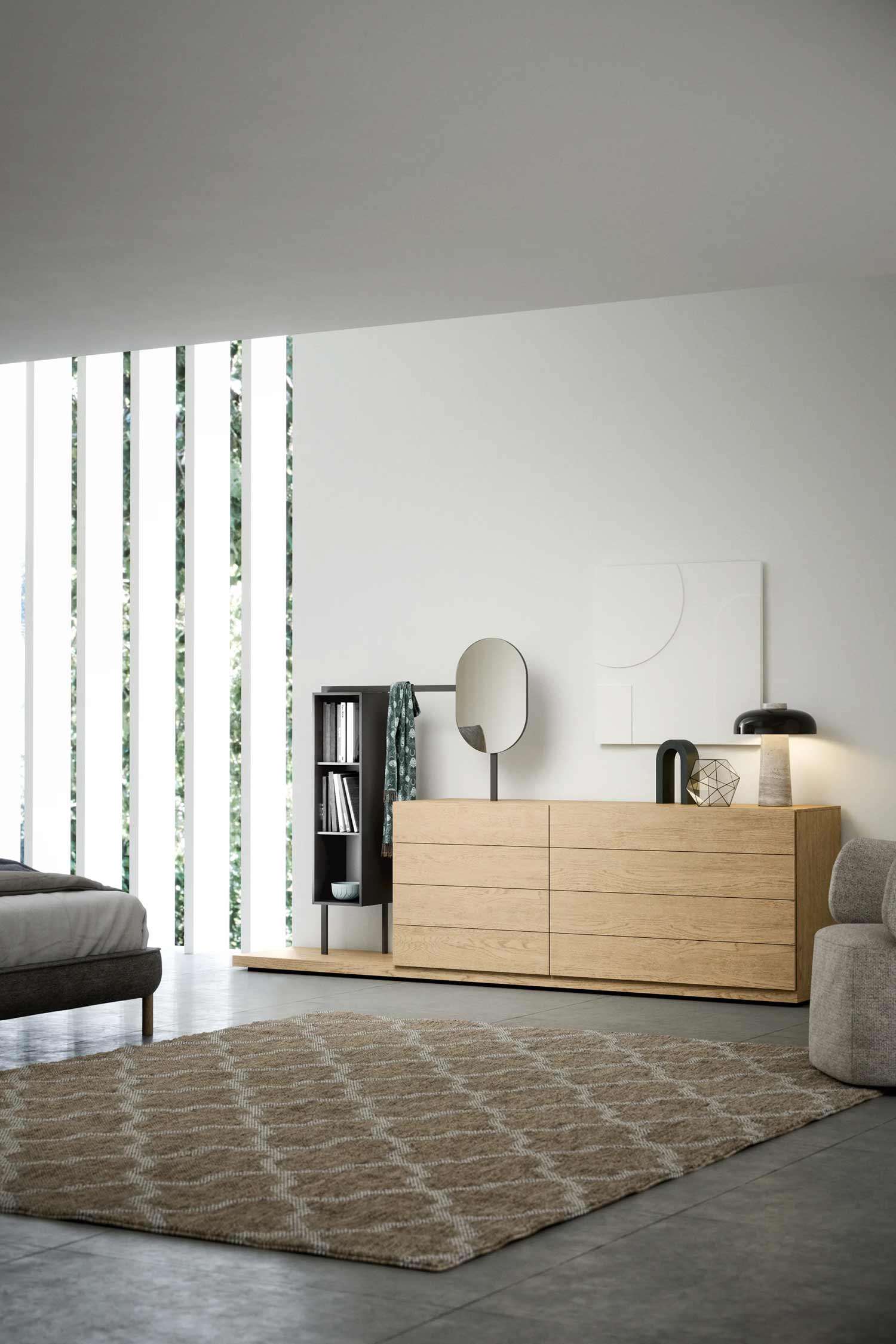 A modern bedroom featuring a light oak six-drawer dresser on a low platform, with a built-in black vertical shelving unit on the left. The dresser is styled with abstract art and a mirror, and the room has large, vertical windows and a neutral woven rug.