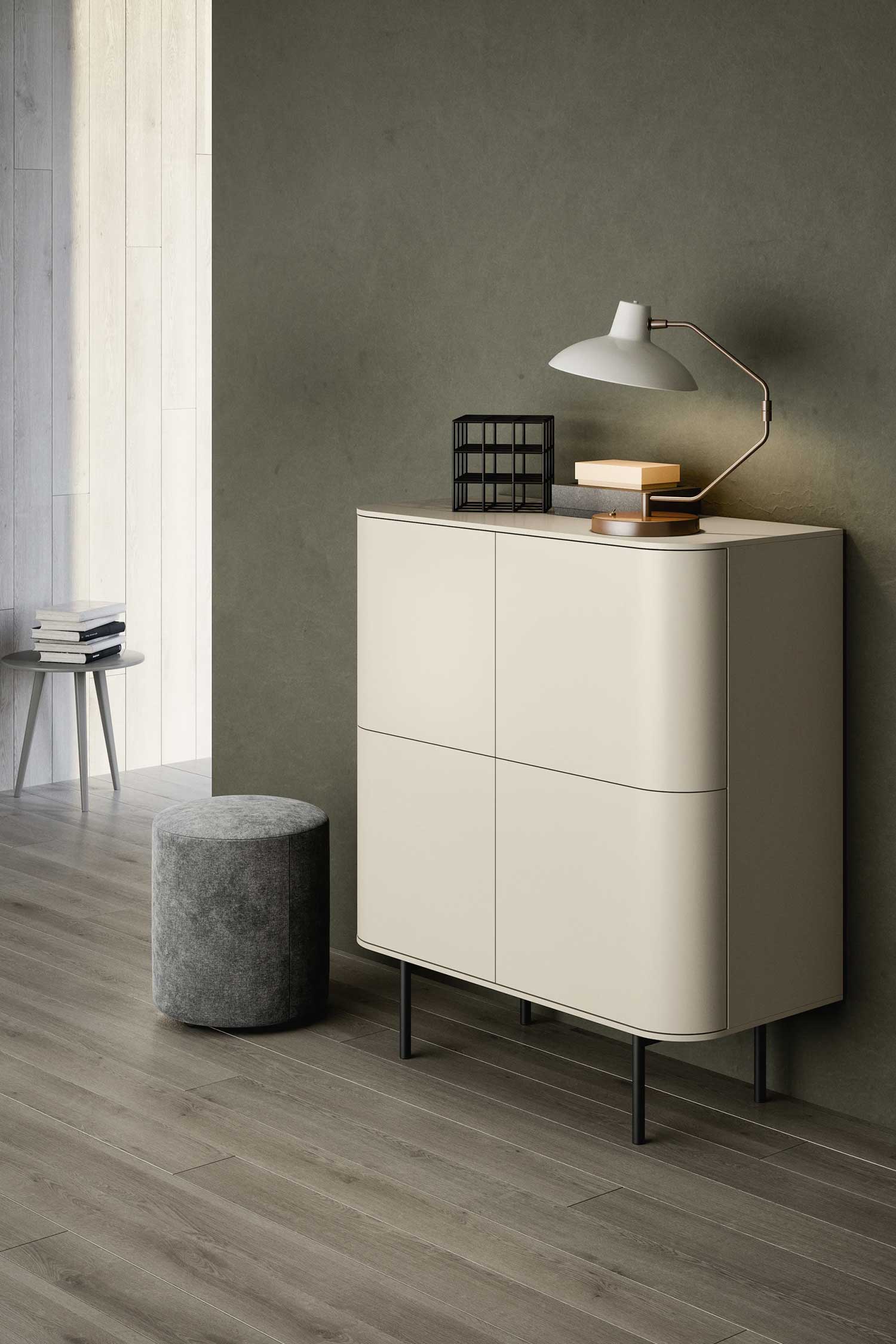A low-angle shot of a terracotta-colored sideboard with two curved, open compartments. Inside the left compartment are two sleek, black bird-shaped figurines. The right compartment has a vertical, light wood back panel. On top of the sideboard rests a fan-shaped, light wood sculpture. A large, abstract, beige wall decoration in the shape of a face is mounted on the wall behind the sideboard.