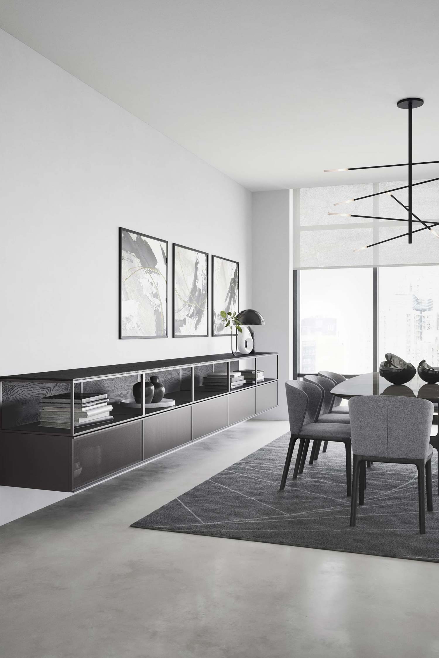 A long, floating, dark brown media console mounted on a white wall in a modern dining room. The console has open shelving with books and decorative vases. Three abstract framed art prints hang above the unit.