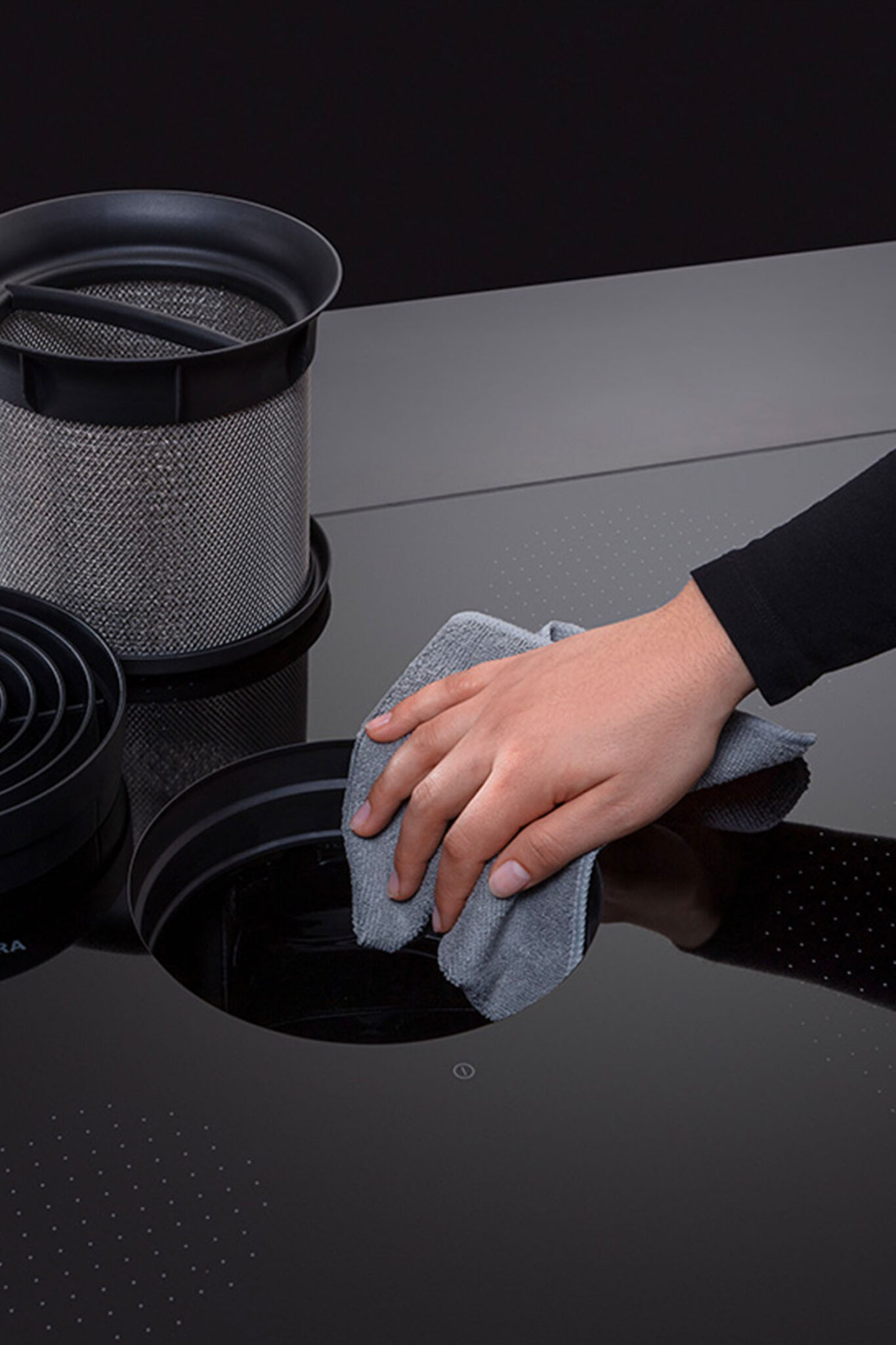 Hand wiping the surface of a BORA Pure S cooktop with the vent removed for cleaning.