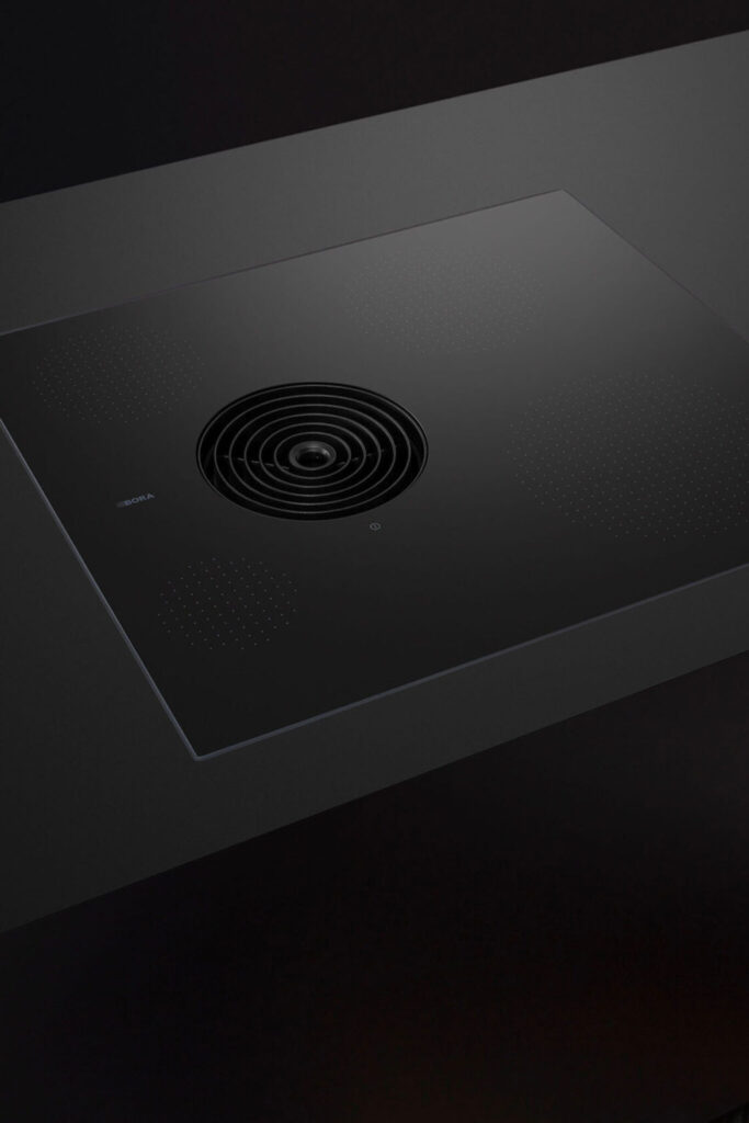 Grey countertop with two pans simmering on a BORA Pure hob and steam drawn into the vent.