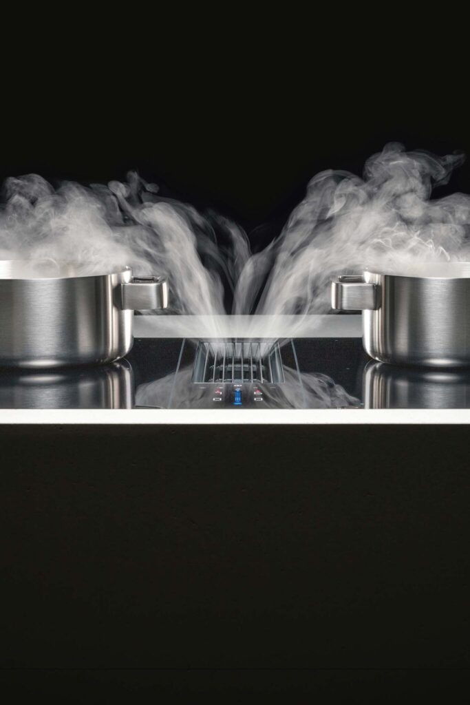 Close-up of steam rising from two pans on a BORA Classic hob with built-in extractor vent between them.