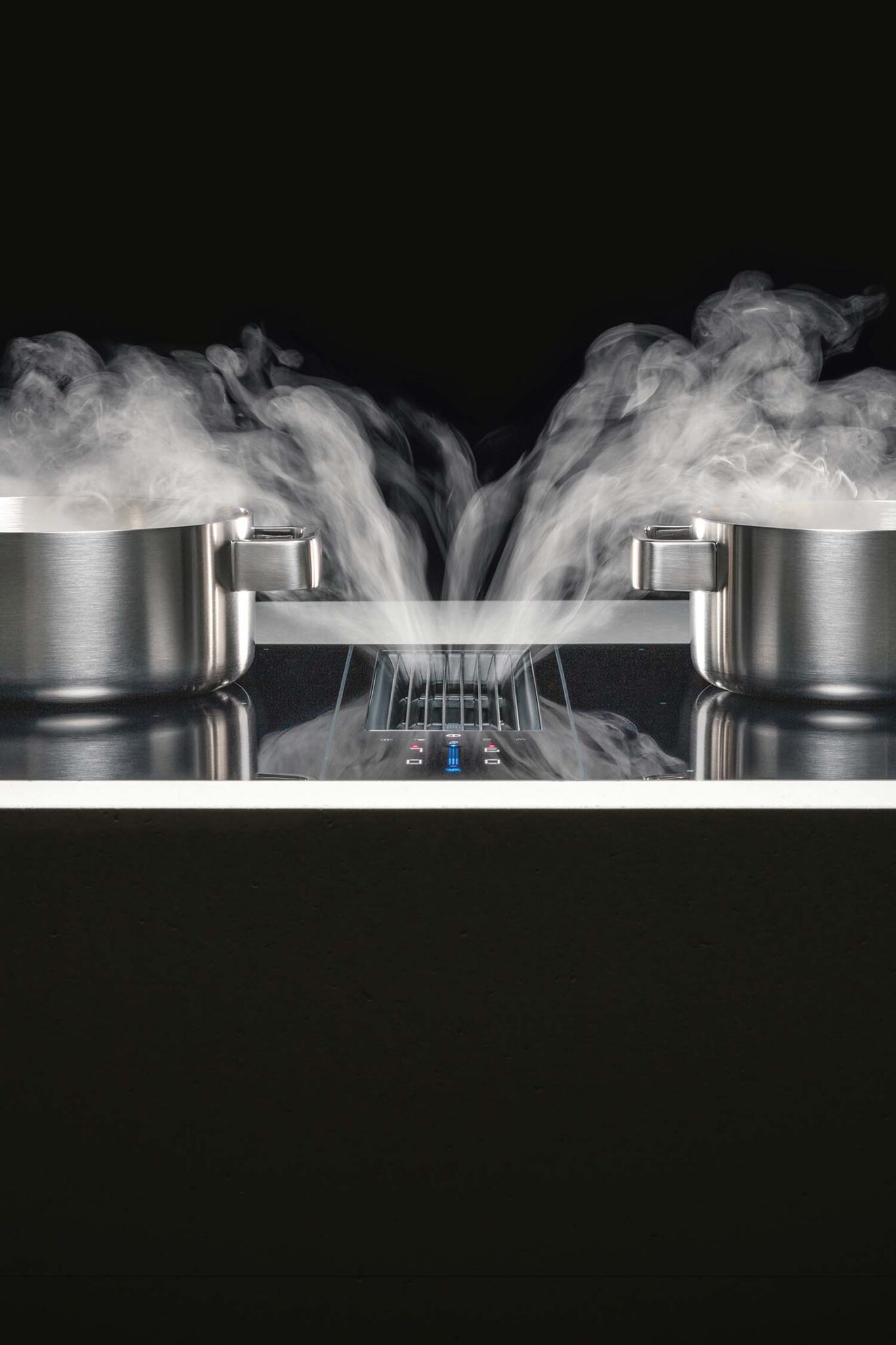 Close-up of steam rising from two pans on a BORA Classic hob with built-in extractor vent between them.