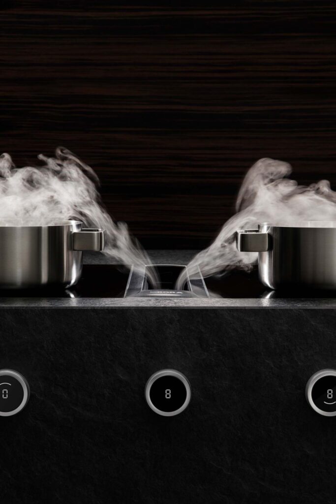 Steam rising from twin pans above a BORA Professional extractor vent built into the hob.