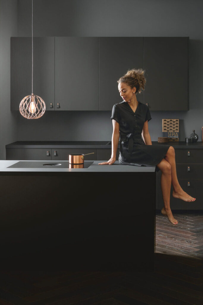 Woman cooking at a kitchen island using a BORA Pure induction hob with integrated extractor.