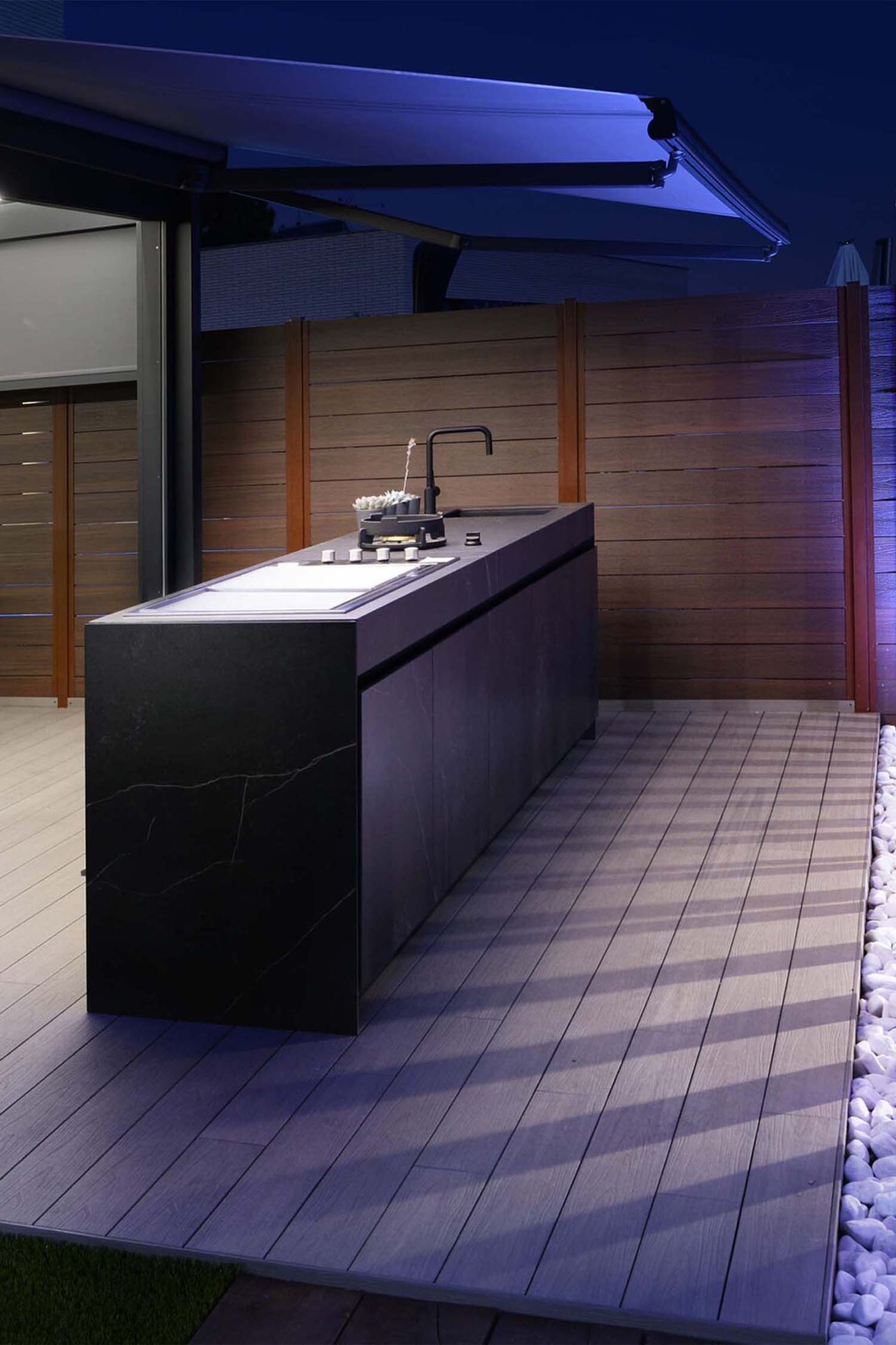 Shot of a luxury stone-effect outdoor kitchen, highlighting the robust, textured cladding and extensive counter space.