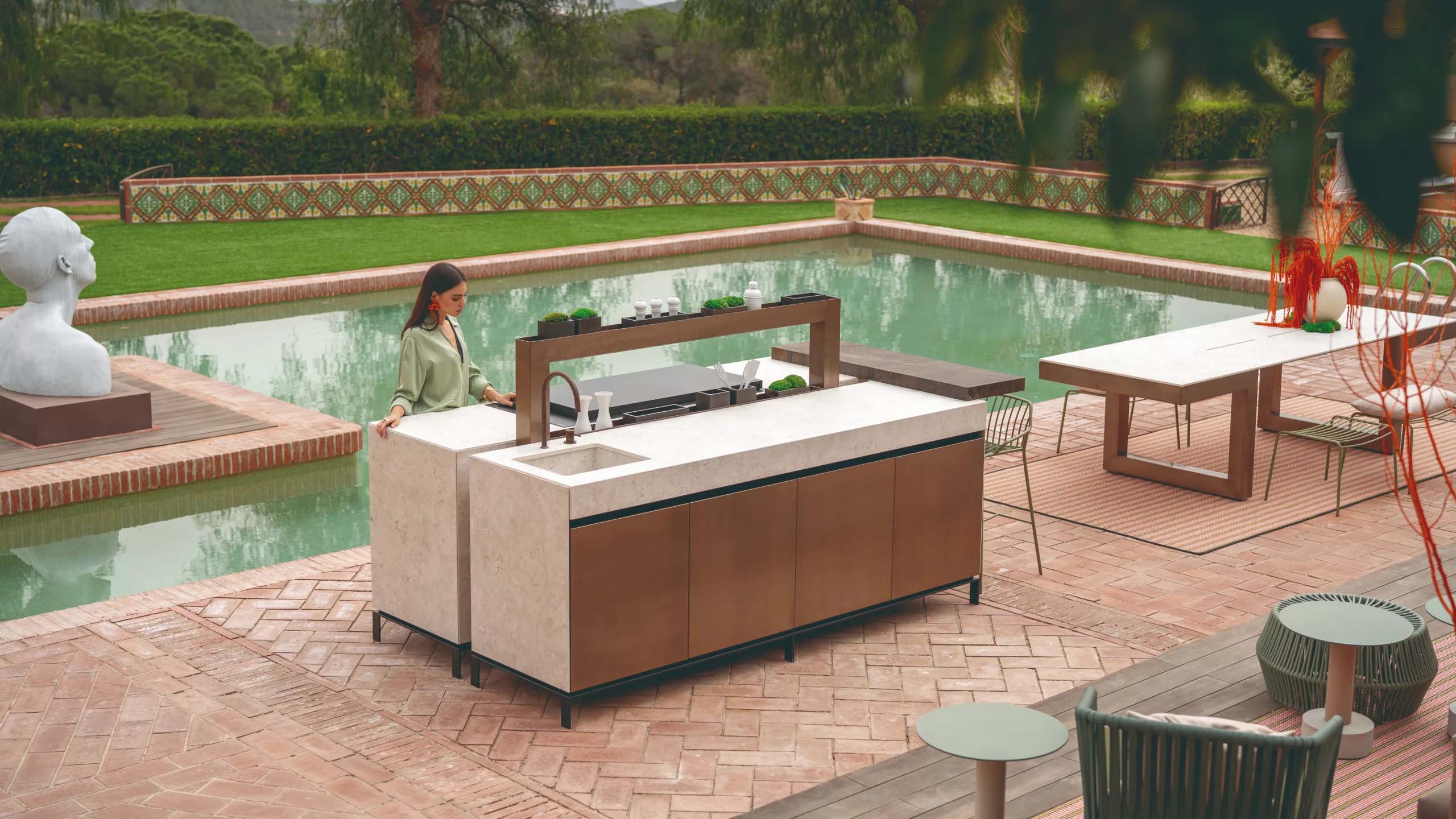 Hero shot of a natural-look luxury outdoor kitchen featuring a large built-in grill, spacious worktop, and integrated greenery planters.