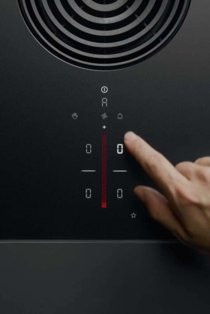 Finger tapping red-lit power symbol on smooth BORA Pure cooktop control panel.
