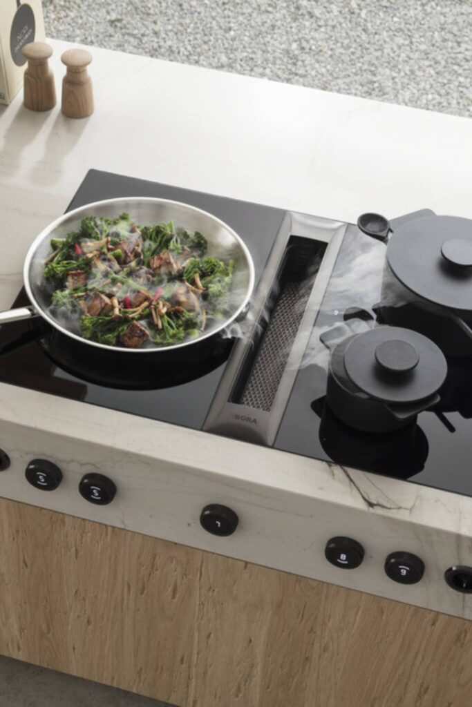 Overhead view of BORA Professional cooktop extracting steam from wok of stir-fried vegetables.