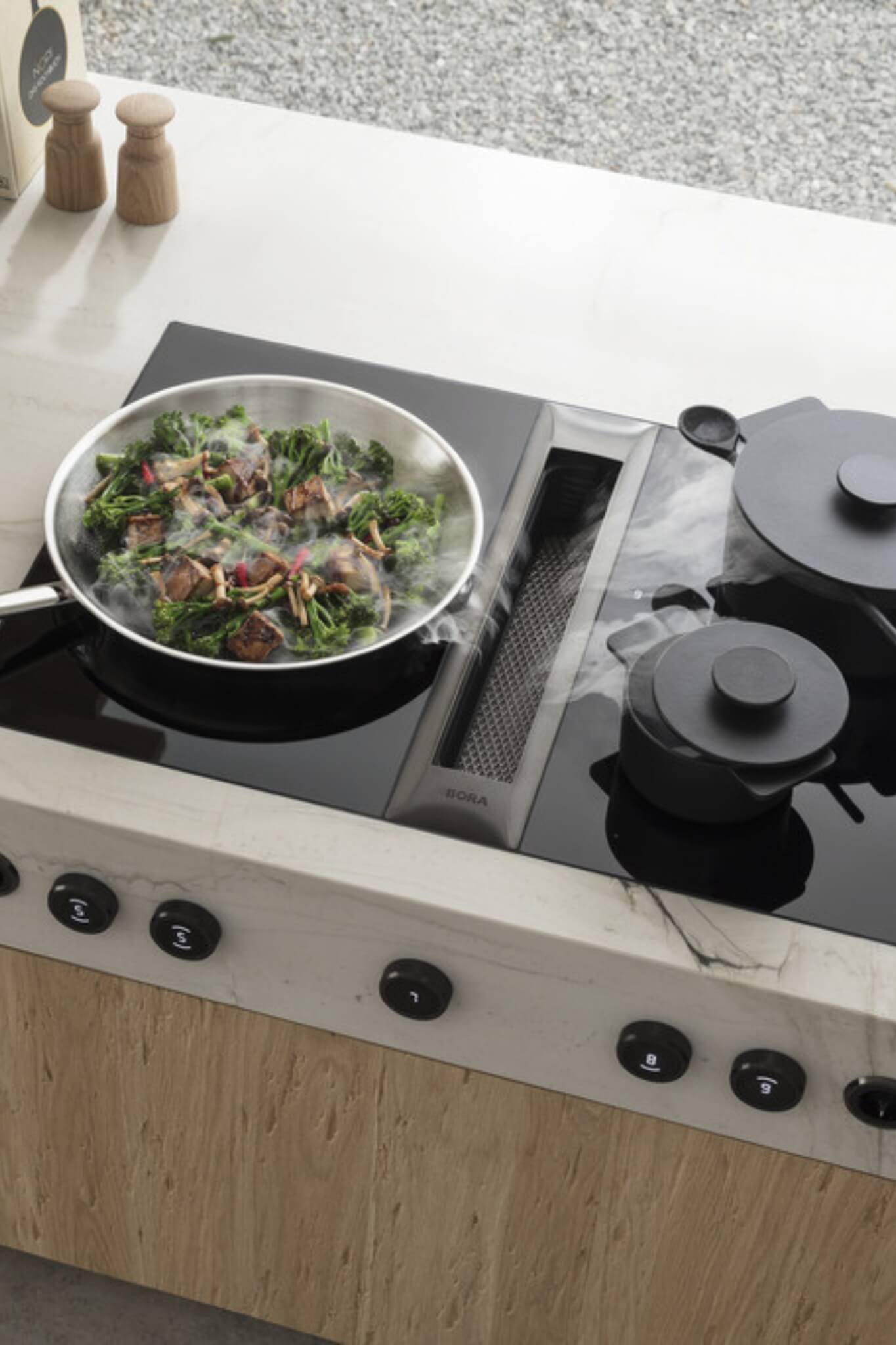 Overhead view of BORA Professional cooktop extracting steam from wok of stir-fried vegetables.
