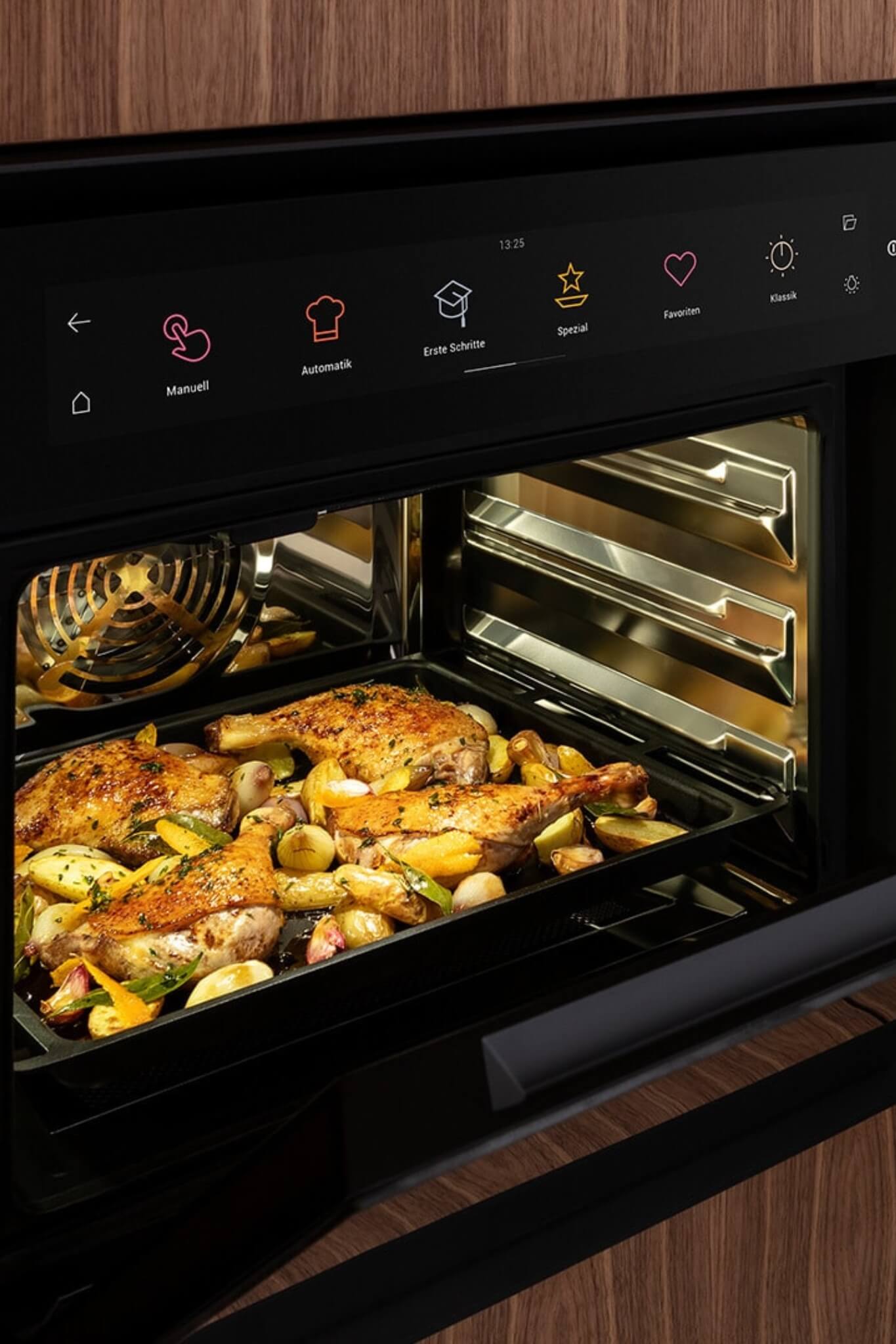 Close-up of BORA XBO oven with roast chicken and vegetables under soft interior lighting.