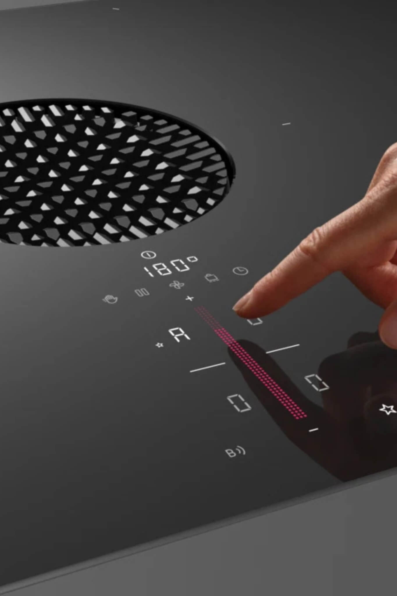 Hand adjusting power level on BORA S Pure induction cooktop with round air inlet and glowing icons.