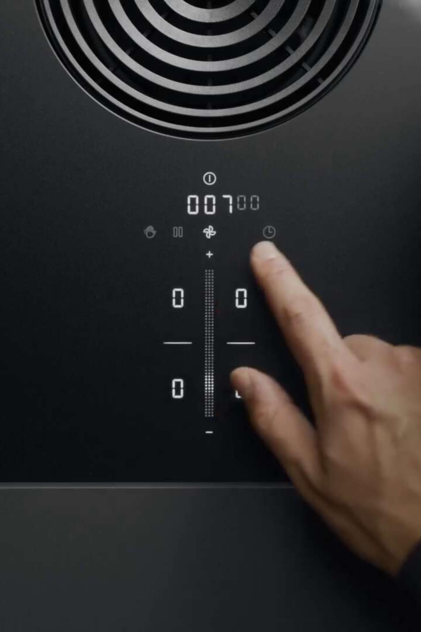 Finger selecting touch controls on sleek black BORA S Pure cooktop with minimalist digital panel.