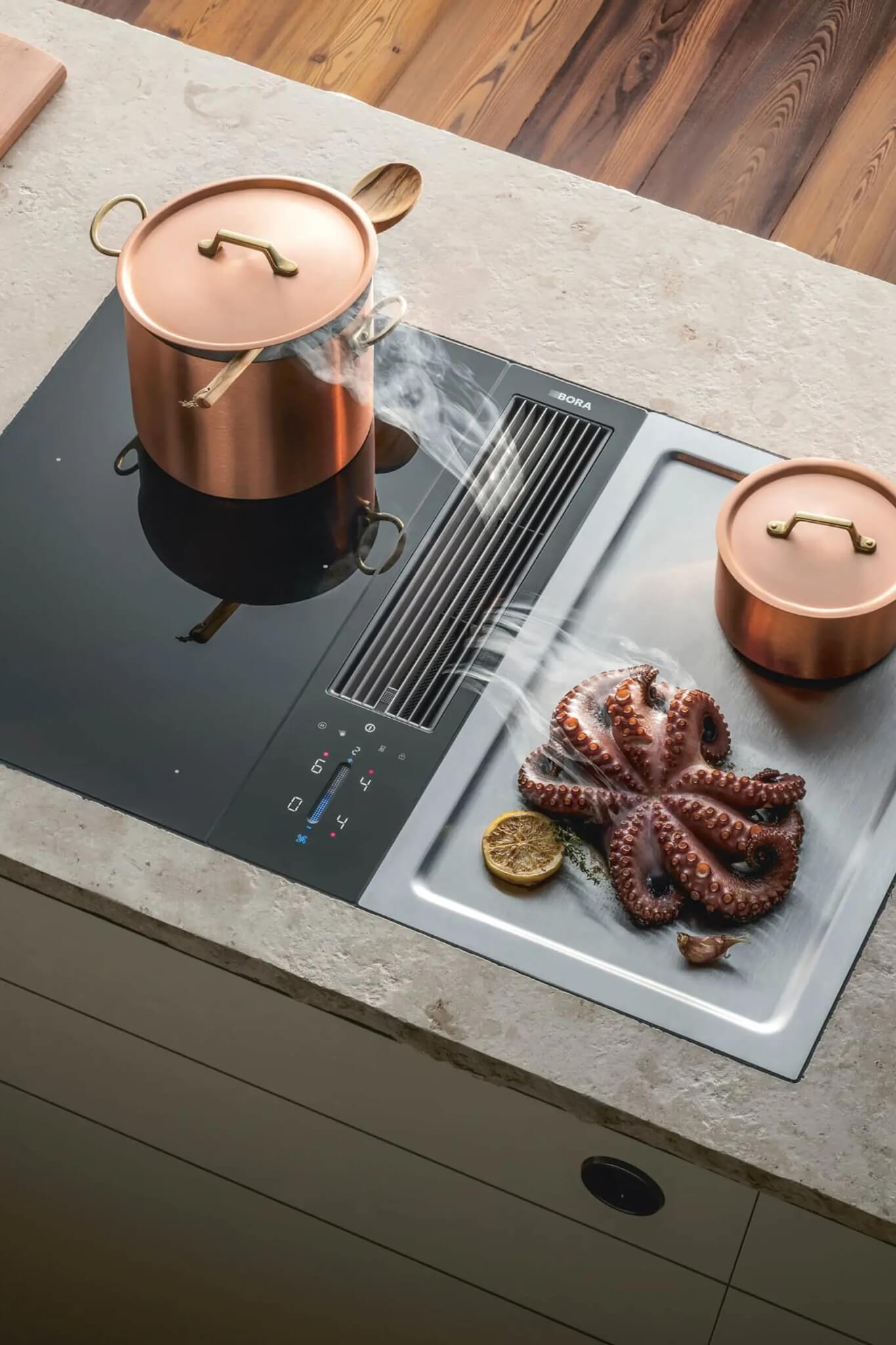 Copper pots cooking sausages on light stone surface with BORA Classic vent between zones.