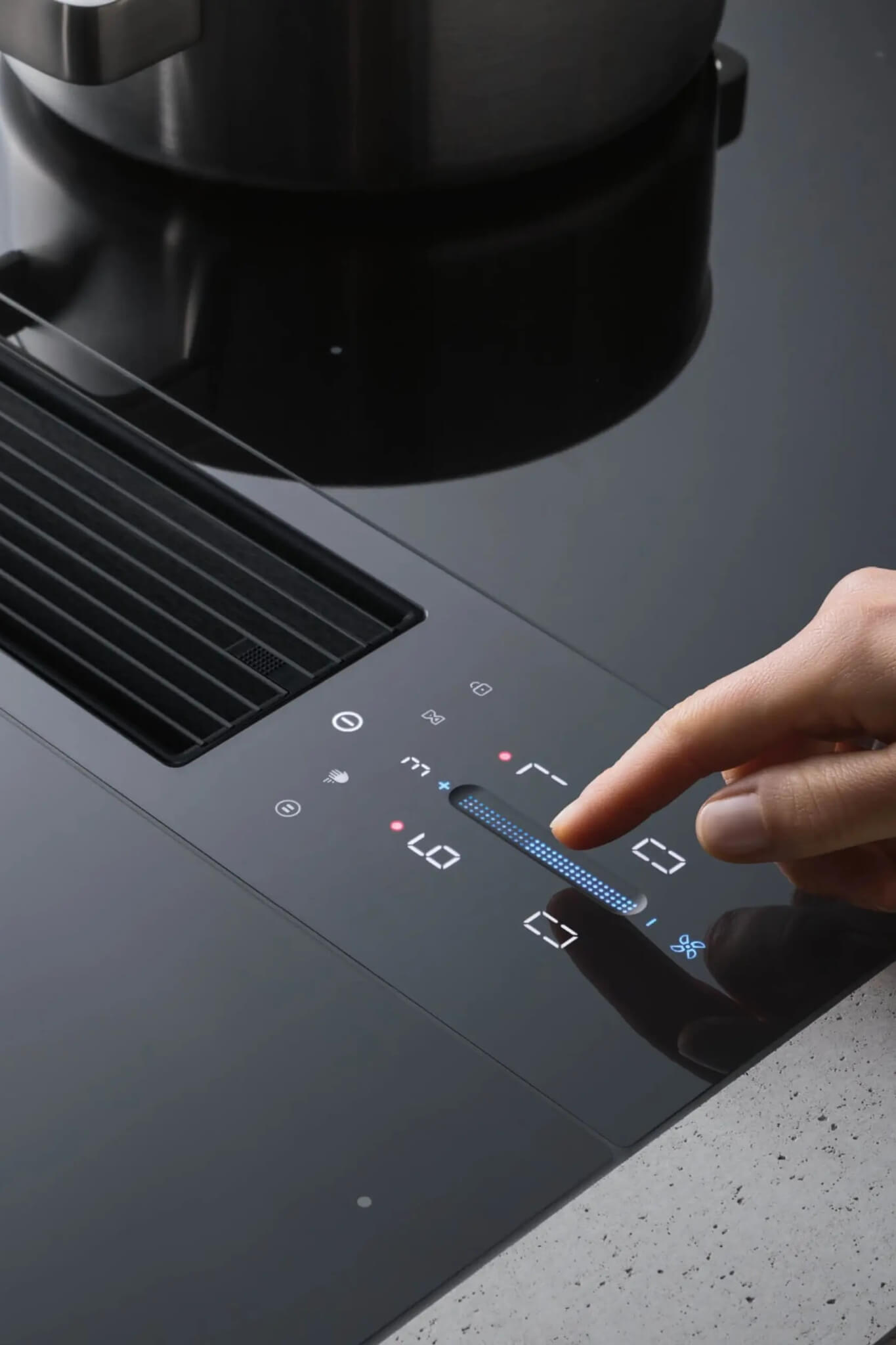 Hand using illuminated slider controls on BORA Classic cooktop’s glossy black panel.